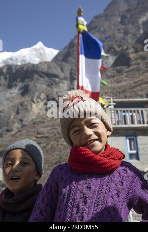 Schüler, Schüler, wie sie außerhalb der örtlichen Schule unter dem Langtang Lirung Peak gesehen werden. Langtang Lirung Peak aus Sicht des Dorfes Langtang, Teil des Langtang Himal Berges in Nepal mit dem höchsten Punkt in einer Höhe von 7234m oder 23734 Fuß. Der Langtang Lirung ist der 99. höchste Berg der Welt und wurde 1978 zum ersten Mal erreicht. Am 25. April 2015 führte ein massives Erdbeben der Stärke 7,8 zu einer Lawine und einem Erdrutsch im Dorf Langtang, bei dem direkt 243 Menschen getötet und das Dorf verschwungen wurden. Der Langtang National Park ist ein beliebtes Trekking- und Reiseland für Fore Stockfoto