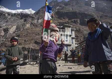 Schüler, Schüler, wie sie außerhalb der örtlichen Schule unter dem Langtang Lirung Peak gesehen werden. Langtang Lirung Peak aus Sicht des Dorfes Langtang, Teil des Langtang Himal Berges in Nepal mit dem höchsten Punkt in einer Höhe von 7234m oder 23734 Fuß. Der Langtang Lirung ist der 99. höchste Berg der Welt und wurde 1978 zum ersten Mal erreicht. Am 25. April 2015 führte ein massives Erdbeben der Stärke 7,8 zu einer Lawine und einem Erdrutsch im Dorf Langtang, bei dem direkt 243 Menschen getötet und das Dorf verschwungen wurden. Der Langtang National Park ist ein beliebtes Trekking- und Reiseland für Fore Stockfoto