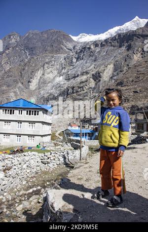 Schüler, Schüler, wie sie außerhalb der örtlichen Schule unter dem Langtang Lirung Peak gesehen werden. Langtang Lirung Peak aus Sicht des Dorfes Langtang, Teil des Langtang Himal Berges in Nepal mit dem höchsten Punkt in einer Höhe von 7234m oder 23734 Fuß. Der Langtang Lirung ist der 99. höchste Berg der Welt und wurde 1978 zum ersten Mal erreicht. Am 25. April 2015 führte ein massives Erdbeben der Stärke 7,8 zu einer Lawine und einem Erdrutsch im Dorf Langtang, bei dem direkt 243 Menschen getötet und das Dorf verschwungen wurden. Der Langtang National Park ist ein beliebtes Trekking- und Reiseland für Fore Stockfoto