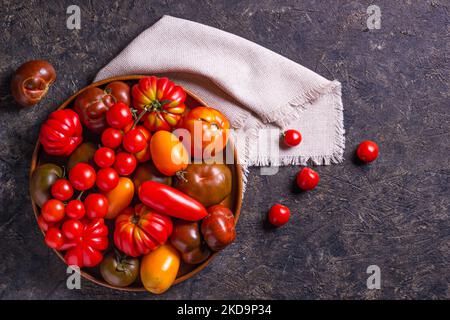 Die Ernte von verschiedenen Tomaten. Bunte Bio-Tomaten auf einem großen Teller. Tomaten verschiedene Sorten. Draufsicht Stockfoto