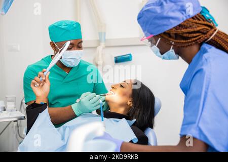 Eine Patientin schaut auf die Zahnärztin und schaut auf ihre Zähne, Zahnarztbesuch . Stockfoto