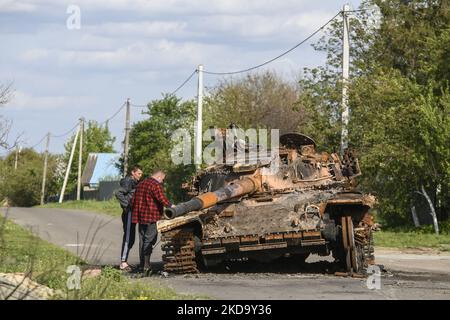 Einheimische Männer erkunden verbrannten Panzer auf der Straße im Dorf Zahaltsi in der Nähe von Kiew, Ukraine, 13. Mai 2022. (Foto von Maxym Marusenko/NurPhoto) Stockfoto