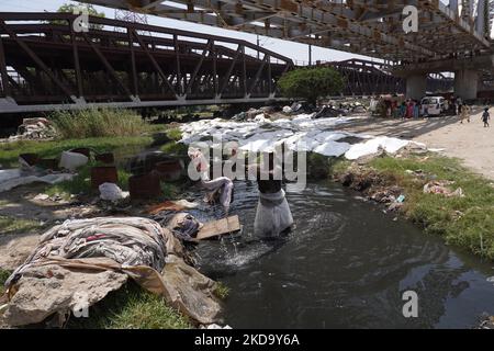 An einem heißen Sommertag in Neu-Delhi, Indien, am 14. Mai 2022 wäscht ein indischer Wäschermann in den verschmutzten Gewässern des Yamuna-Flusses Kleidung. Der „Weltklimatag“ wird jedes Jahr am 15. Mai begangen, um auf eine Vielzahl von Umweltbelangen, insbesondere den globalen Klimawandel, aufmerksam zu machen. (Foto von Mayank Makhija/NurPhoto) Stockfoto