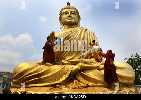 Ein indischer buddhistischer Mönch klettert auf eine riesige Buddha-Statue, um sich am Vorabend von Buddha Purnima zu waschen und zu schmücken, einem traditionellen Feiertag, der am 15. Mai 2021 in Howrah, Westbengalen, Indien, zum Geburtstag Buddhas, auch bekannt als Vesak-Feiern, gefeiert wird.Buddha Purnima feiert den 16. Mai. (Foto von Debajyoti Chakraborty/NurPhoto) Stockfoto