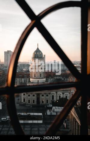 Eine Vertikale der Neuen Kirche auf dem Gendarmenmarkt in Berlin, Deutschland bei Sonnenuntergang hinter Metallbarren Stockfoto