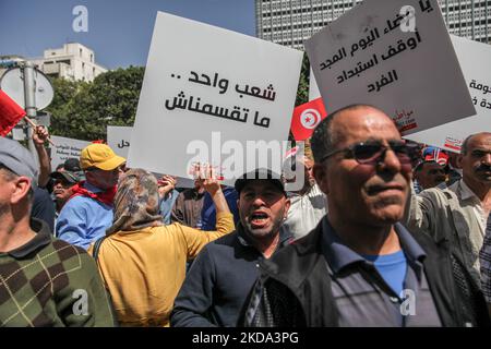 Eine Frau hebt ein Plakat auf, das auf Arabisch steht: Wir sind ein vereintes Volk, teilen Sie uns nicht, während einer Demonstration von Anhängern der Bewegung Bürger gegen den Putsch - die Demokratische Initiative, die Nationale Heilsfront und die islamistische Partei Ennahda, auf der Avenue Habib Bourguiba in Tunis statt, Tunesien, am 15. Mai 2022, um gegen den tunesischen Präsidenten Kais Saied und seine außergewöhnlichen Maßnahmen zu protestieren, die er seit Juli 2021 ergriffen hat. Die Demonstranten forderten die Absetzung von Präsident Kais Saied und den Sturz des von ihnen so genannten diktatorischen Regimes und forderten die Rückkehr der demokratischen Institutionen Stockfoto