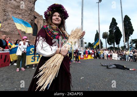 Eine Ansicht einer Frau in Veschywanka (dem traditionellen ukrainischen bestickten Hemd), die ein Kind festhält, und Putin, der mit blutigen Händen vorrückt, während einer Flashmob der ukrainischen Gemeinschaft in Rom, Italien, während einer Demonstration, die aufgerufen wurde, „keinen Krieg mehr“ zu sagen, am 22. Mai 2022 in Rom, Italien, eine Sense zu fassen. (Foto von Andrea Ronchini/NurPhoto) Stockfoto