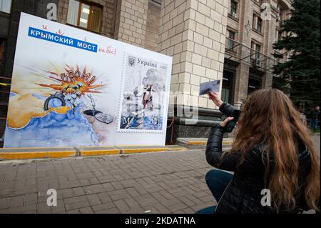 Kiew, Kiew, Ukraine. 4.. November 2022. Eine Frau fotografiert ein Wandbild, das eine Briefmarke mit einem Bild der Zerstörung der "Krimbrücke" zeigt, eine 2 Milliarden Dollar teure Struktur, die von Russland auf der besetzten Krim gebaut wurde. Russland begann 2014 einen Krieg gegen die Ukraine. Russland begann am 24. Februar 2022 eine umfassende Invasion der Ukraine. (Bild: © Danylo Antoniuk/ZUMA Press Wire) Stockfoto