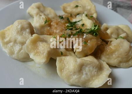 Ein Teller mit ukrainischen Pierogi (gefüllte Knödel) mit gebratenen Zwiebeln serviert an einer Milchbar in Krakau. Aufgrund der aktuellen Ereignisse in der Ukraine (2022 russische Invasion in der Ukraine) entfernen viele Gastronomen aus ganz Polen „russische Knödel“ von der Speisekarte und ändern den Namen in „ukrainische“ Knödel. Am Mittwoch, den 23. Mai 2022, fand in Krakau, der Woiwodschaft Kleinpolen, Polen. (Foto von Artur Widak/NurPhoto) Stockfoto