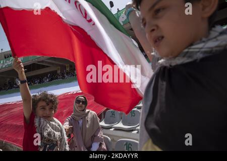 Zwei iranische Schüler schwenken iranische Flaggen, während sie neben ihrer Mutter stehen, während sie an einer Versammlung teilnehmen, in der sie die Hymne „Hallo Kommandant“ im Azadi (Freiheit) Fußballstadion im Westen von Teheran zur Unterstützung des iranischen Obersten Führers Ayatollah Ali Khamenei am 26. Mai gesungen haben. 2022. Hunderttausend Anhänger des iranischen Obersten Führers Ayatollah Ali Khamenei versammelten sich im Sportkomplex Azadi (Freiheit), um den Hymnus Hallo Kommandant zu singen. (Foto von Morteza Nikoubazl/NurPhoto) Stockfoto