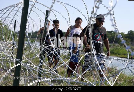 Migranten, die meisten mit Kindern, folgen einem Weg entlang des Konzertsaals, wo sie nach der Überquerung des Rio Grande am 27 2022. Mai im Eagle Pass Texas, USA, von Border Patrol unter Bewachung gestellt werden. Titel 42, das Mandat der Trump-Ära, das Migranten die Einreise in die USA verhindern sollte, Sollte am 23. Mai auslaufen, wurde aber durch eine Klage blockiert, die von mehreren Staaten eingereicht wurde und darauf hinweist, dass der Schritt zum Streik des Gesetzes „die Standards des Verwaltungsverfahrensgesetzes nicht erfüllt“ und dass es keine dauerhafte Lösung für den Umgang mit dem unvermeidlichen Anstieg der Einwanderung gibt. Gegner zum Aufhalten von Stockfoto