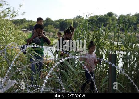 Migranten, die meisten mit Kindern, folgen einem Weg entlang des Konzertsaals, wo sie nach der Überquerung des Rio Grande am 27 2022. Mai im Eagle Pass Texas, USA, von Border Patrol unter Bewachung gestellt werden. Titel 42, das Mandat der Trump-Ära, das Migranten die Einreise in die USA verhindern sollte, Sollte am 23. Mai auslaufen, wurde aber durch eine Klage blockiert, die von mehreren Staaten eingereicht wurde und darauf hinweist, dass der Schritt zum Streik des Gesetzes „die Standards des Verwaltungsverfahrensgesetzes nicht erfüllt“ und dass es keine dauerhafte Lösung für den Umgang mit dem unvermeidlichen Anstieg der Einwanderung gibt. Gegner zum Aufhalten von Stockfoto