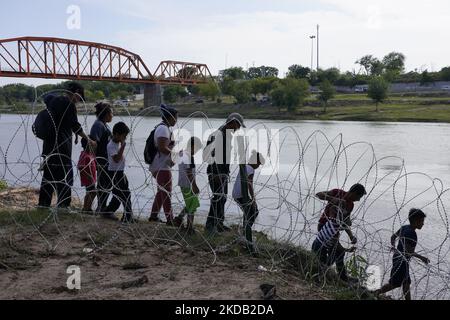 Migranten, die meisten mit Kindern, folgen einem Weg entlang des Konzertsaals, wo sie nach der Überquerung des Rio Grande am 27 2022. Mai im Eagle Pass Texas, USA, von Border Patrol unter Bewachung gestellt werden. Titel 42, das Mandat der Trump-Ära, das Migranten die Einreise in die USA verhindern sollte, Sollte am 23. Mai auslaufen, wurde aber durch eine Klage blockiert, die von mehreren Staaten eingereicht wurde und darauf hinweist, dass der Schritt zum Streik des Gesetzes „die Standards des Verwaltungsverfahrensgesetzes nicht erfüllt“ und dass es keine dauerhafte Lösung für den Umgang mit dem unvermeidlichen Anstieg der Einwanderung gibt. Gegner zum Aufhalten von Stockfoto