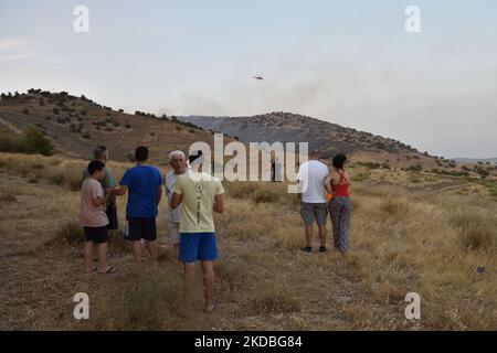 Athen, Griechenland. 4.. Juni 2022. Bewohner beobachten, wie Feuerwehrhubschrauber in der Region Voula operieren. Ein Waldbrand bricht über die Hänge des Berges Hymettus und zwingt die Behörden, Bewohner in einigen Gebieten der südlichen Vororte in Athen, Griechenland, zu evakuieren. (Foto von Nicolas Koutsokostas/NurPhoto) Stockfoto