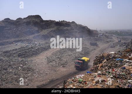 Ein LKW transportiert Müll zur Müllkippe, während Rauch von einem brennenden Müllhügel nach einem Brand auf der Mülldeponie Bhalswen am Weltumwelttag in Neu-Delhi, Indien, am 5. Juni 2022 aufflacht. (Foto von Mayank Makhija/NurPhoto) Stockfoto