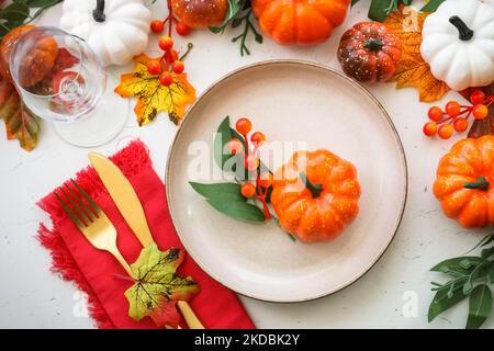 Herbsttischeinstellung. Weißer Teller, goldenes Besteck und Herbstdekorationen. Stockfoto