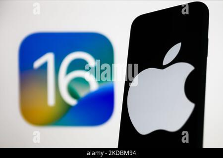 Das Apple-Logo auf einem Telefonbildschirm und das iOS 16-Logo auf einem Bildschirm im Hintergrund sind auf diesem Illustrationsfoto zu sehen, das am 6. Juni 2022 in Krakau, Polen, aufgenommen wurde. (Foto von Jakub Porzycki/NurPhoto) Stockfoto
