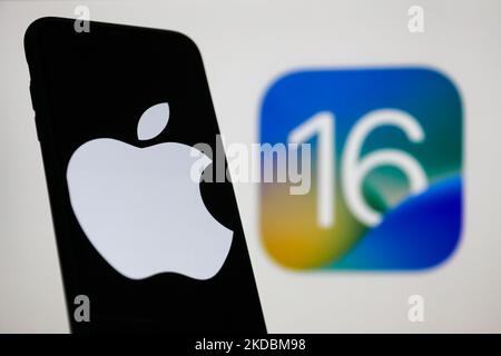 Das Apple-Logo auf einem Telefonbildschirm und das iOS 16-Logo auf einem Bildschirm im Hintergrund sind auf diesem Illustrationsfoto zu sehen, das am 6. Juni 2022 in Krakau, Polen, aufgenommen wurde. (Foto von Jakub Porzycki/NurPhoto) Stockfoto