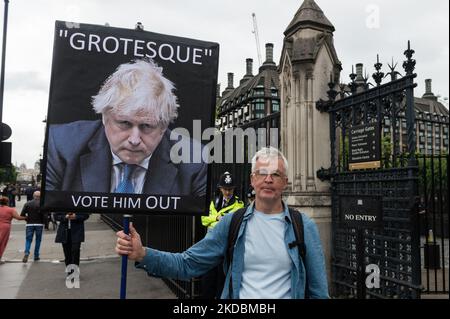 LONDON, VEREINIGTES KÖNIGREICH - 06. JUNI 2022: Ein Demonstranten hält ein Plakat vor dem Parlamentsgebäude, während Abgeordnete der Konservativen Partei am 06. Juni 2022 in London, England, bei einer Vertrauensabstimmung vor Premierminister Boris Johnson ihre Stimme abgegeben haben. Das Vertrauensvotum wurde ausgelöst, nachdem mindestens 54 Abgeordnete ihre Misstrauensbriefe an Sir Graham Brady, den Vorsitzenden des konservativen Ausschusses 1922 für die Hinterbank, eingereicht hatten, nachdem Sue Grays Bericht in Covid-Sperrparteien in der Downing Street veröffentlicht worden war. (Foto von Wiktor Szymanowicz/NurPhoto) Stockfoto