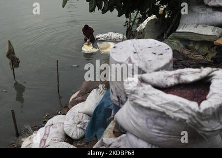 Am 08. Juni 2022 reinigt ein Arbeiter im Buriganga River in Dhaka, Bangladesch, Plastiksäcke mit Chemikalien. Der Buriganga-Fluss, der durch die Stadt Dhaka fließt, ist heute einer der am stärksten verschmutzten Flüsse des Landes, da dort immer mehr Menschen- und Industrieabfälle abgeführt werden. (Foto von Syed Mahamudur Rahman/NurPhoto) Stockfoto