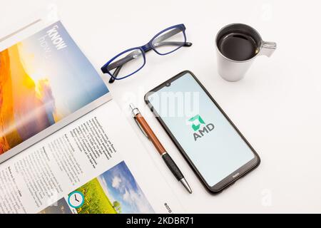 In dieser Fotobilder ist ein AMD-Logo (Advanced Micro Devices) zu sehen, das am 9. Juni 2022 auf einem Smartphone-Bildschirm auf einem Schreibtisch neben einem Café, einem Stift, einer Brille und einem Magazin in Athen, Griechenland, zu sehen ist. (Foto-Illustration von Nikolas Kokovlis/NurPhoto) Stockfoto