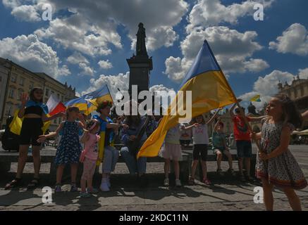 Svetlana Nikonorova, eine ukrainische Sängerin und Bandura-Spielerin, umringt von Kindern, spielt während des Protestes ein Lied. Mitglieder der lokalen ukrainischen Diaspora, Kriegsflüchtlinge, Friedensaktivisten, Freiwillige und lokale Unterstützer während des 109.-tägigen „Protestes der NATO Close the Sky“ am Adam-Mickiewicz-Denkmal auf dem Hauptplatz in Krakau. Am Sonntag, den 12. Juni 2022, in Krakau, Polen. (Foto von Artur Widak/NurPhoto) Stockfoto