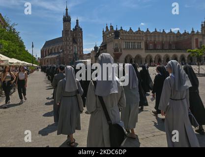 Mitglieder der örtlichen weiblichen religiösen Gemeinden marschieren während der Fronleichnamsprozession auf dem Krakauer Marktplatz. Das Fronleichnamsfest, auch bekannt als Hochfest des heiligsten Leibes und Blutes Christi, ist eine katholische liturgische Feierlichkeit, die die wahre Gegenwart von Leib und Blut, Seele und Göttlichkeit Jesu Christi in den Elementen der Eucharistie feiert. Am Donnerstag, den 16. Juni 2022, in Krakau, Polen. (Foto von Artur Widak/NurPhoto) Stockfoto