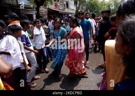 Frauen tanzen in Trance, während hinduistische Anhänger mit einem Metallspieß, der durch ihren Mund durchbohrt wird, an einer religiösen Prozession anlässlich des „Muthu Mariamman“-Festivals in Neu-Delhi, Indien, am 26. Juni 2022 teilnehmen. Das Festival, das in Indien und dem südasiatischen Subkontinent gefeiert wird, wo es bedeutende tamilische Gemeinschaften gibt, bietet eine der extremsten religiösen Andachtsäußerungen der Welt. (Foto von Mayank Makhija/NurPhoto) Stockfoto