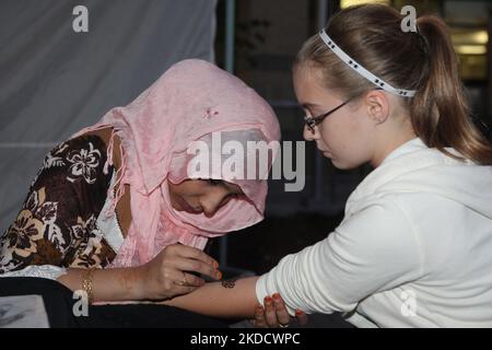 Eine pakistanische Frau trägt während des Mosaic South Asian Heritage Festival in Mississauga, Ontario, Kanada, am 16. August 2013 Henna auf den Arm eines kanadischen Mädchens. (Foto von Creative Touch Imaging Ltd./NurPhoto) Stockfoto