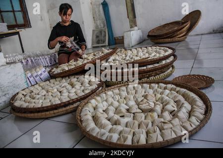 Am 29. Juni 2022 wird in Cihampelas, Cililin, West Bandung Regency, eine Frau beim Verpacken traditioneller Wajit-Lebensmittel beobachtet. West-Java, Indonesien. Die Händler sagten, dass Ende Juni 2022 der Umsatz mit traditionellen Lebensmitteln Wajit Cililin um bis zu 60 Prozent gestiegen ist oder neun Tonnen pro Monat verkaufen könnte, verglichen mit dem Vorjahr, das aufgrund von COVID-19 nur drei Tonnen pro Monat verkaufte. Wajit ist ein traditionelles Essen, typisch für Cililin, West Bandung Regency, das aus klejedem Reis, Palmzucker und Kokosnuss hergestellt wird. (Foto von Algi Febri Sugita/NurPhoto) Stockfoto