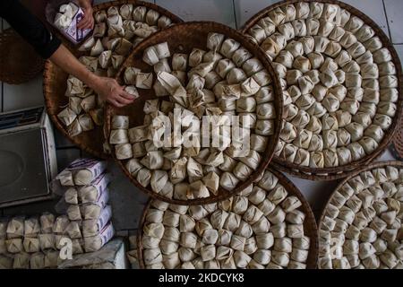 Am 29. Juni 2022 wird in Cihampelas, Cililin, West Bandung Regency, eine Frau beim Verpacken traditioneller Wajit-Lebensmittel beobachtet. West-Java, Indonesien. Die Händler sagten, dass Ende Juni 2022 der Umsatz mit traditionellen Lebensmitteln Wajit Cililin um bis zu 60 Prozent gestiegen ist oder neun Tonnen pro Monat verkaufen könnte, verglichen mit dem Vorjahr, das aufgrund von COVID-19 nur drei Tonnen pro Monat verkaufte. Wajit ist ein traditionelles Essen, typisch für Cililin, West Bandung Regency, das aus klejedem Reis, Palmzucker und Kokosnuss hergestellt wird. (Foto von Algi Febri Sugita/NurPhoto) Stockfoto