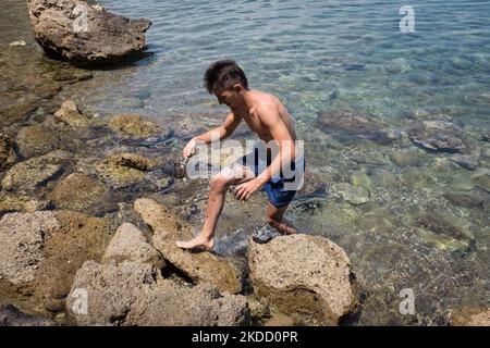 Am 30. Juni 2022 fängt ein Mann am Strand von Skliri auf der griechischen Insel Aigina lila Quallen mit einer türkischen Kaffeekocher. Viele Quallen erschienen an den Stränden aufgrund der starken Winde in Griechenland. (Foto von Nikolas Kokovlis/NurPhoto) Stockfoto