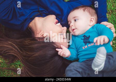 Ein Blick von oben auf die Mutter und den Sohn, die auf dem Gras liegen und kuscheln Stockfoto