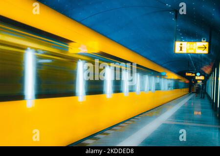 Eine lange Exposition eines gelben Zuges, der am Bahnhof vorbeifährt, in der U-Bahn, in Berlin, Deutschland Stockfoto