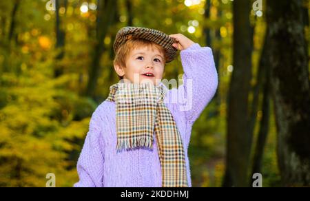 Fröhliches Kind Junge in Pullover, Schal und Mütze. Fröhliches Kind im Herbstpark. Mode für Kinder. Stockfoto