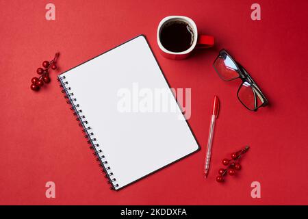 Ein offener Notizblock, Stift, Brille und Kaffee auf rotem Hintergrund mit Platz für Text oder Bild Stockfoto