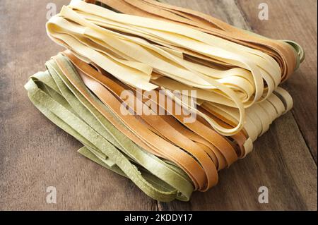 Hausgemachte getrocknete Tagliatelle Nudeln in drei Sorten, einfach, grün und braun, zur Verwendung als Zutat in der italienischen oder mediterranen Küche, hohe Angl Stockfoto