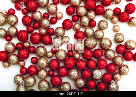 Glänzende goldene und rote Kugeln auf weißem Hintergrund. Flach liegend, Draufsicht. Cristmas Grußkarte. Stockfoto