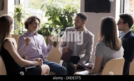 Fünf Mitarbeiter nehmen an der im Büro versammelten Gruppenbesprechung Teil Stockfoto