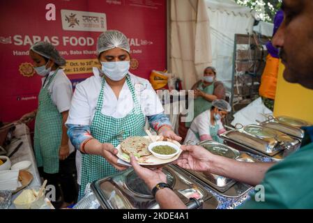 Frauen aus staatlichen Selbsthilfegruppen von Haryana, die Bajre KI roti (Indian Pearl Millet Bread) mit saag, einem traditionellen Essen aus Nordindien, während des Saras Food Festivals, das vom Ministerium für ländliche Entwicklung in Baba Kharak Singh Marg, Connaught Place, organisiert wurde. Das Saras Food Festival ist ein einzigartiges Beispiel für die Ermächtigung von Frauen. Etwa 150 Unternehmerinnen und Mitglieder von Selbsthilfegruppen (Selbsthilfegruppen sind ein Finanzintermediärkomitee, das in der Regel aus 12 bis 25 lokalen Frauen im Alter zwischen 18 und 50 Jahren besteht) aus 17 Staaten nehmen an dieser Veranstaltung Teil, die ihnen die Möglichkeit gibt, ihre eigenen Projekte zu präsentieren Stockfoto