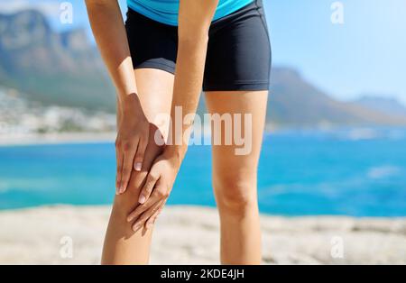 Denken Sie immer daran, sich zu strecken. Eine sportliche junge Frau, die an einer Sportverletzung leidet. Stockfoto