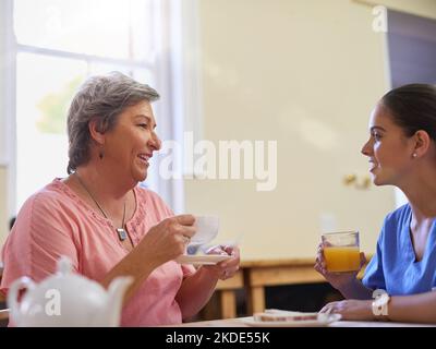 Tee wird immer mit einer Seite des chit Chat serviert. Ein Betreuer im Gespräch mit einem älteren Patienten in einem Pflegeheim. Stockfoto