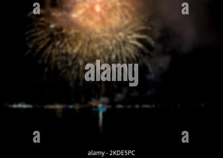Abstraktes, defokussiertes Feuerwerk im Hintergrund grüßt nachts über der Meeresbucht Stockfoto