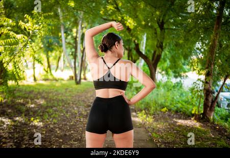 Sportliche Frau macht vor dem Laufen Dehnübungen. Athlet Girl streckt die Arme vor dem Laufen. Konzept der körperlichen Aktivität und gesundes Leben Stockfoto