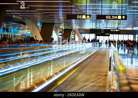 Transportieren Sie Ihr Gepäck auf einfache Weise. Bewegliche Gehwege in einem überfüllten Wartebereich am Flughafen. Stockfoto