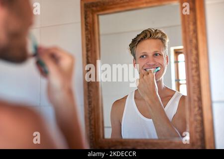 Das einzige Funkeln, das ich brauche, ist in meinem Mund. Ein junger Mann, der sich im Badezimmer die Zähne putzt. Stockfoto