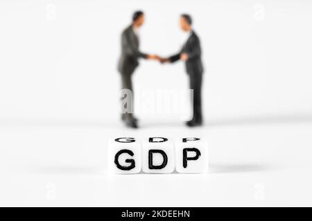 GDP auf Perlen mit zwei Maßstab Modell Geschäftsleute, schüttelt die Hände, im Hintergrund. Britain Cost of Living Crisis Concept Stockfoto