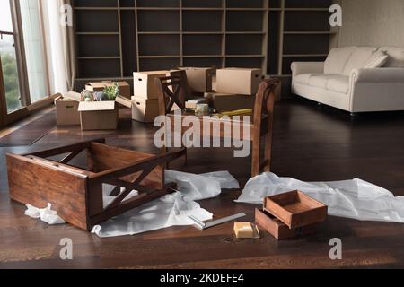 Unmontierte Möbel und Kartons auf dem Boden im Wohnzimmer Stockfoto