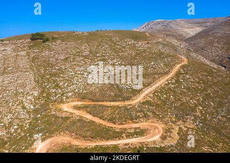 Spektakuläre Luftaufnahme mit Serpentinen-Off-Road-Strecke zum Gipfel des Attavyros-Berges. Höchster Berg auf der Insel Rhodos, Griechenland. Stockfoto