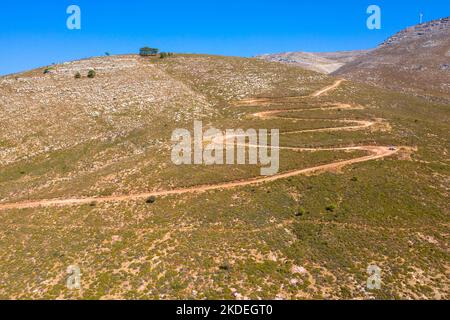 Spektakuläre Luftaufnahme mit Serpentinen-Off-Road-Strecke zum Gipfel des Attavyros-Berges. Höchster Berg auf der Insel Rhodos, Griechenland. Stockfoto